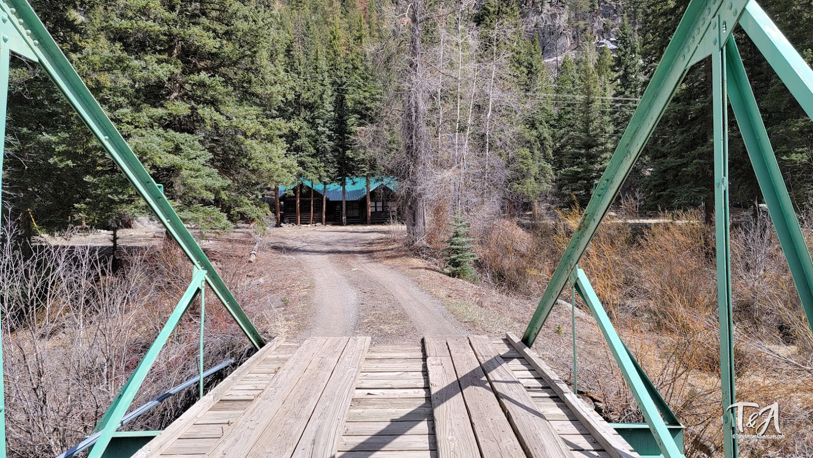 A cool wooden bridge leading to cabins over a river in Colorado.
